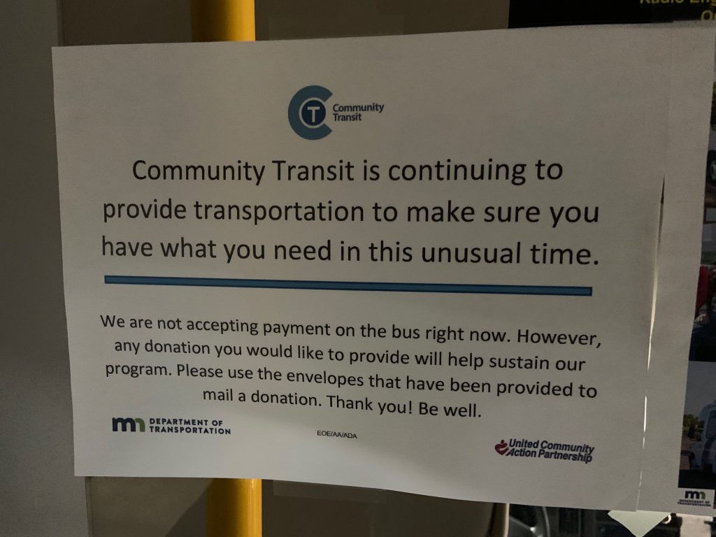 Sign that reads "Community Transit is continuing to provide transportation to make sure you have what you need in this unusual time. We are not accepting payment on the bus right now. However, any donation you provide will help us sustain our program. Please use the envelopes that have been provided to mail a donation Thank you! Be well.