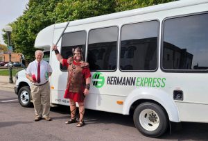 Picture of Hermann Express transit bus at the ribbon cutting event with New Ulm mascot, Hermann the German, standing by it.