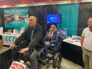 photo of trike at a display booth with a couple trying it out