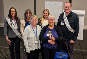 Group photo of four women and a man in a conference room.